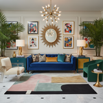 Modern living room with a blue sofa, colorful rug, and decorative wall art.