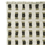 Close-up view of a contemporary hand-knotted wool rug with a geometric pattern, perfect for enhancing living room area rugs. The design features a grid of black and olive rectangles on a neutral background, showcasing modern elegance in area rugs.