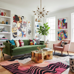 Modern living room with a green sofa, colorful rug, and abstract art.