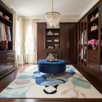 Luxurious bedroom with dark wood wardrobes, a blue ottoman, and a colorful rug.