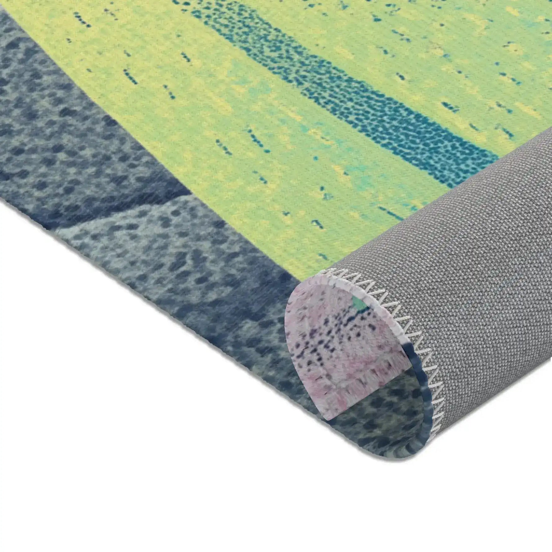 Corner fold showing yellow-green teal speckled print face and grey anti-slip backed overlock stitching, Mystic Guardian Accent Rug