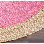 A vibrant and natural bordered bright pink round jute area rug, perfect for adding a boho touch to your living room. The rug features a pink center with a natural jute border, showcasing a textured weave that's ideal for any space.