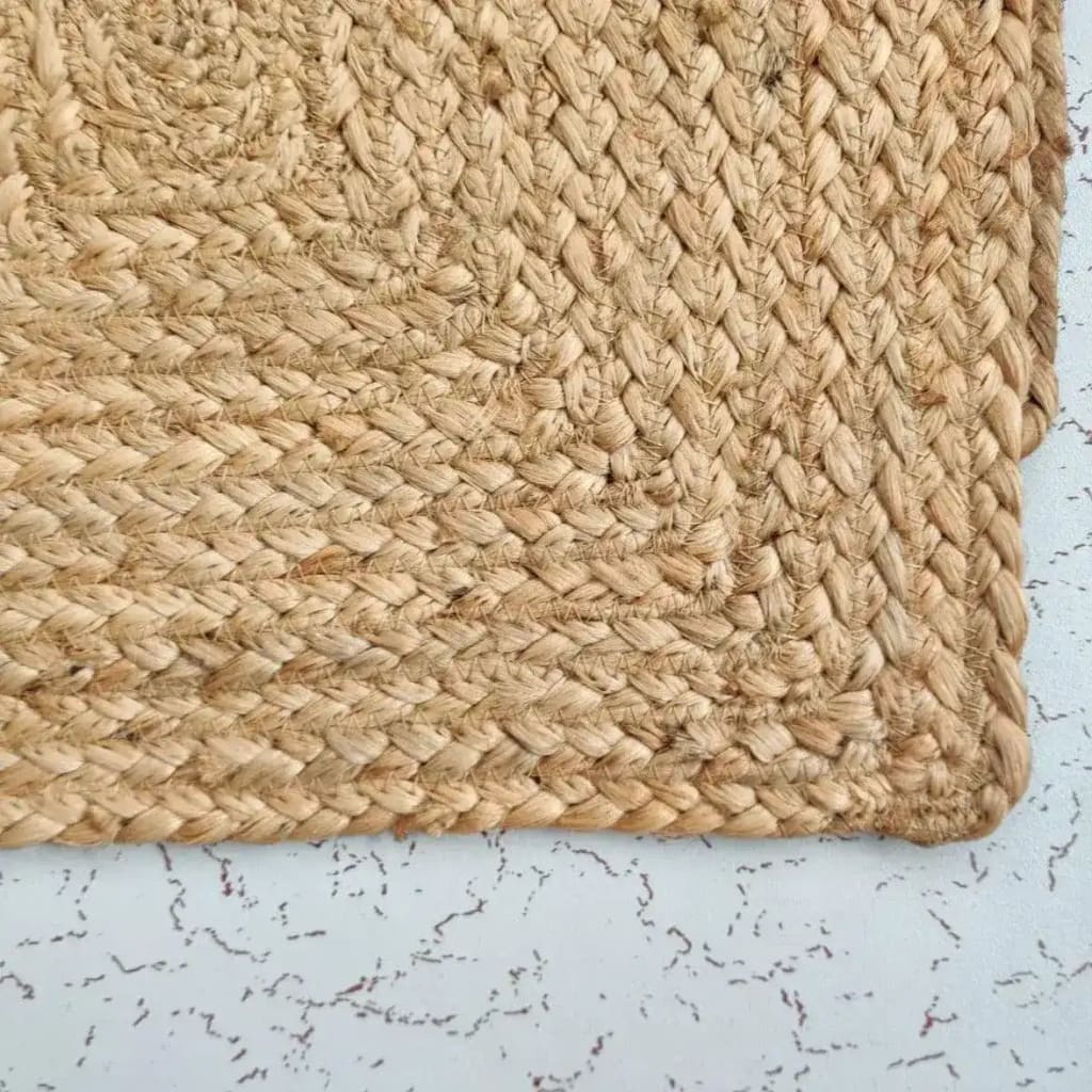 Close-up view of a natural braided rectangular jute rug, showcasing the intricate weave and texture. Perfect for use as an area rug in living rooms, kitchens, or offices, this jute rug adds a rustic touch to any space.
