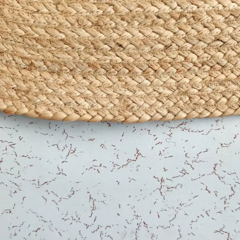 Close-up view of a Natural Oval Jute Rug, showcasing its intricate braided texture, perfect for use as an area rug in living rooms, kitchens, or hallways. Ideal for adding a touch of rustic charm to your bedroom or as a stylish kitchen runner rug.