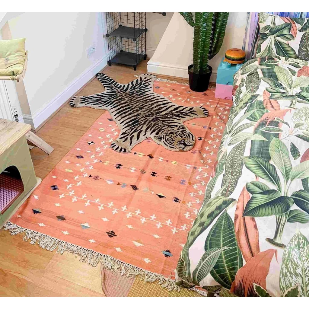 A beautifully designed blush galaxy cotton area rug in a living room setting, featuring a unique tiger pattern in the center. This reversible boho rug displays intricate natural vegetable dye patterns, enhancing the cozy ambiance of the space. Perfect for those seeking stylish living room area rugs with a touch of exotic flair.