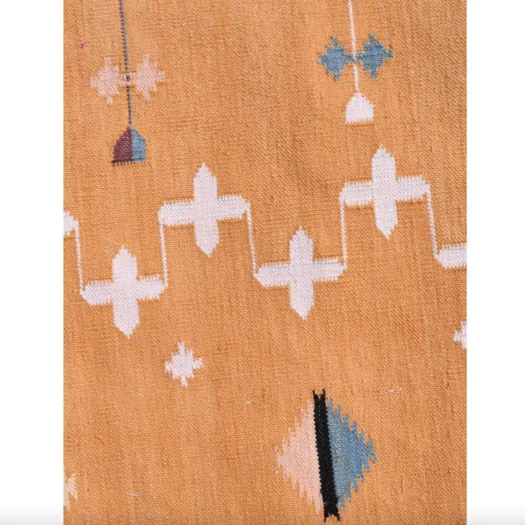 Close-up view of a Natural Vegetable Dyed Indian Dhurrie Reversible Cotton Rug in a mustard color, featuring geometric patterns. Perfect as an area rug for a dining room, this boho rug adds a touch of elegance under a dining table.