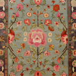 A beautifully detailed floral rug showcasing vibrant pink and red flowers on a soft blue background. This hand-knotted area rug, perfect for enhancing living room decor, exudes the timeless elegance and intricate design typical of Persian rugs. An ideal choice for those seeking exquisite living room area rugs.