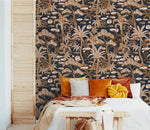 Navy copper palm tree wallpaper behind a bed with rust and mustard pillows in a cozy bedroom