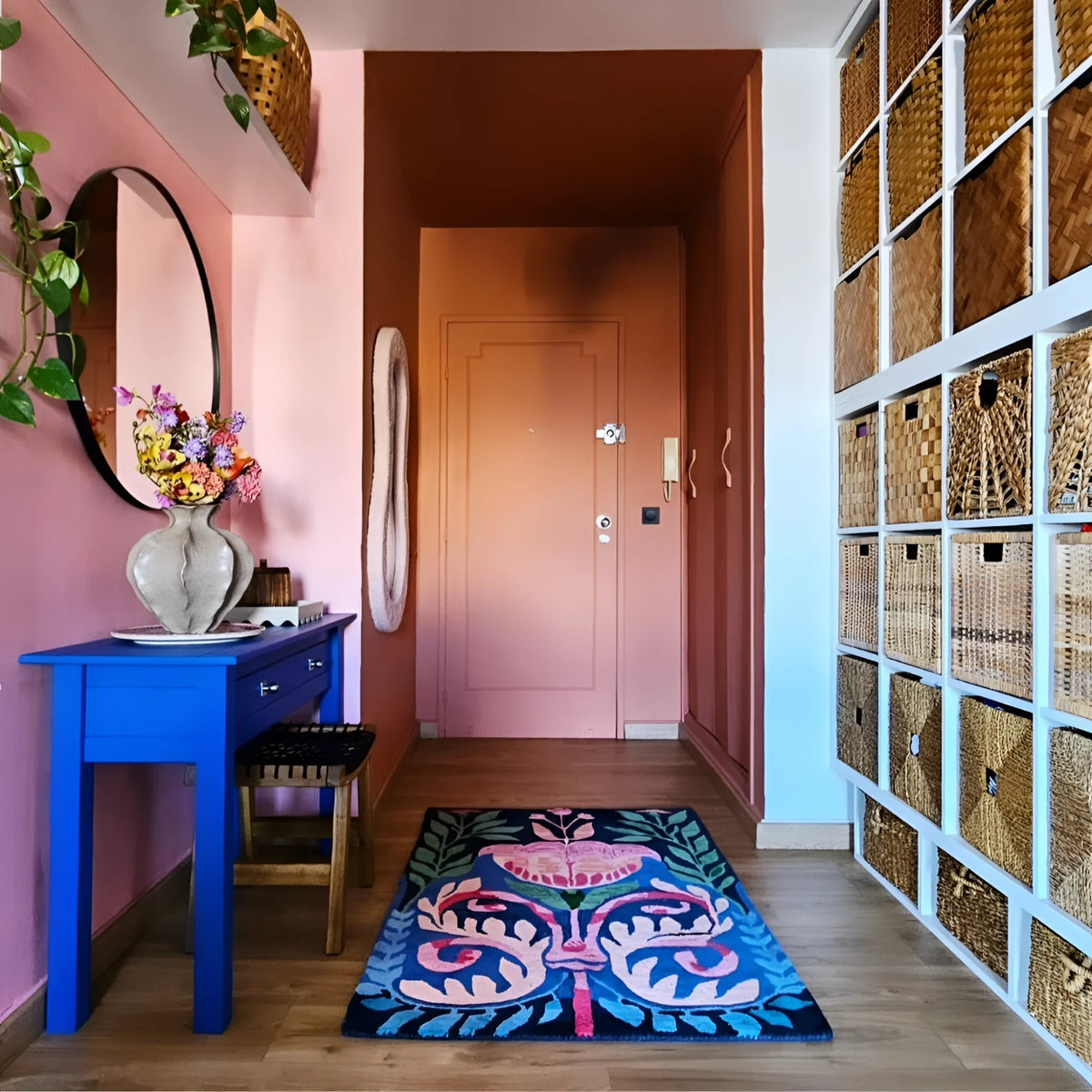 Navy floral Serenade rug on wood floor in a pink-walled entry with blue console and baskets