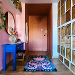 Navy floral Serenade rug on wood floor in a pink-walled entry with blue console and baskets