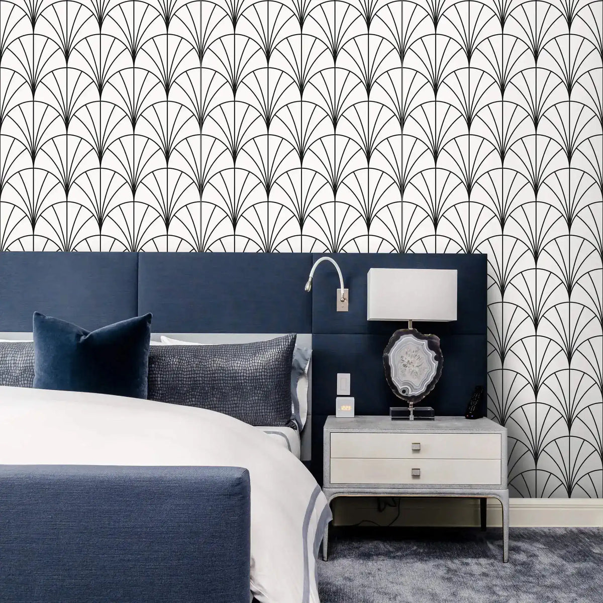 Navy headboard and lamp against monochrome round line wallpaper of black-and-white arches