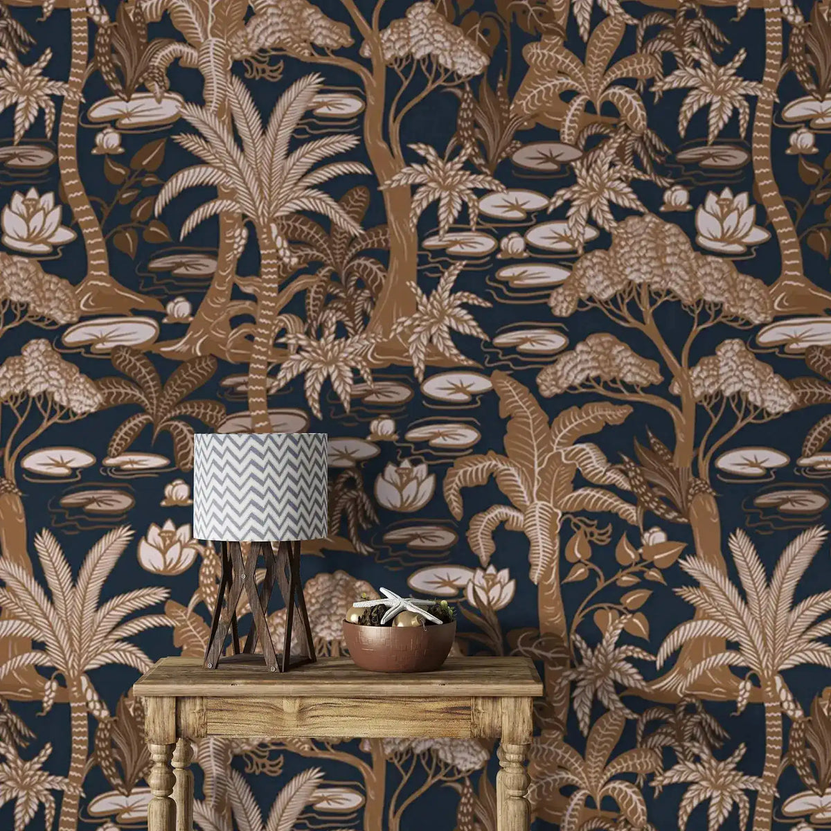 Navy palm tree wallpaper in copper tones behind a rustic console table with lamp and bowl