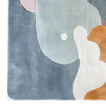 Top view of a vibrant area rug showcasing a blend of blue, white, and orange abstract shapes. This hand-tufted wool rug is perfect for adding a modern touch to living rooms. Ideal for spaces needing an 8x10 size rug.