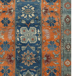 A vibrant Nomadic Heritage Knotted Wool Rug showcasing intricate vintage patterns in rich orange and blue hues. Perfect for adding a touch of elegance to your dining room or bedroom, this wool rug enhances both living room and dining room spaces with its timeless design.