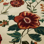 Close-up of a floral patterned rug with red flowers and green leaves.