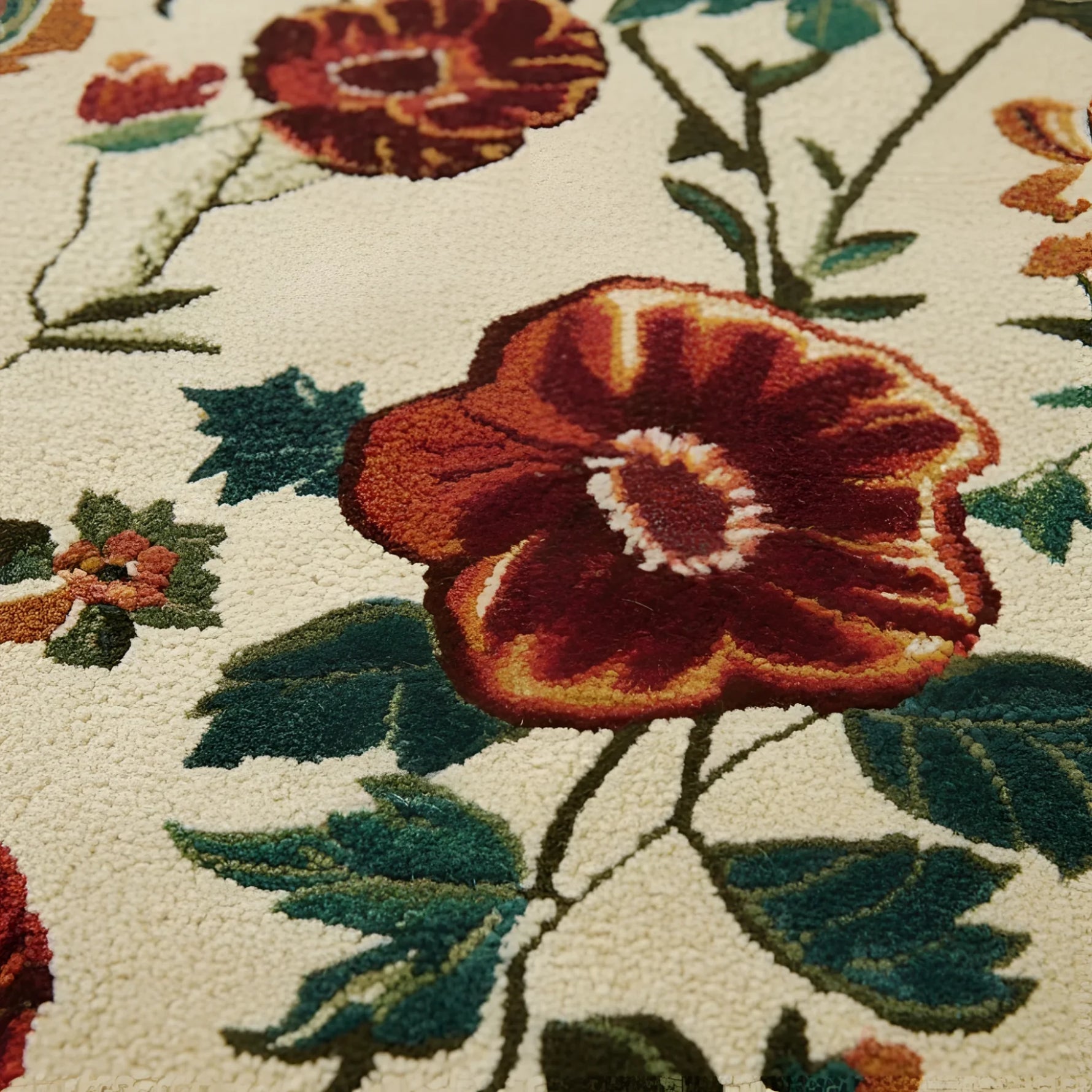 Close-up of a floral patterned rug with red flowers and green leaves.