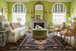 Living room with green walls, floral knotted rug, a white sofa, and decorative elements.