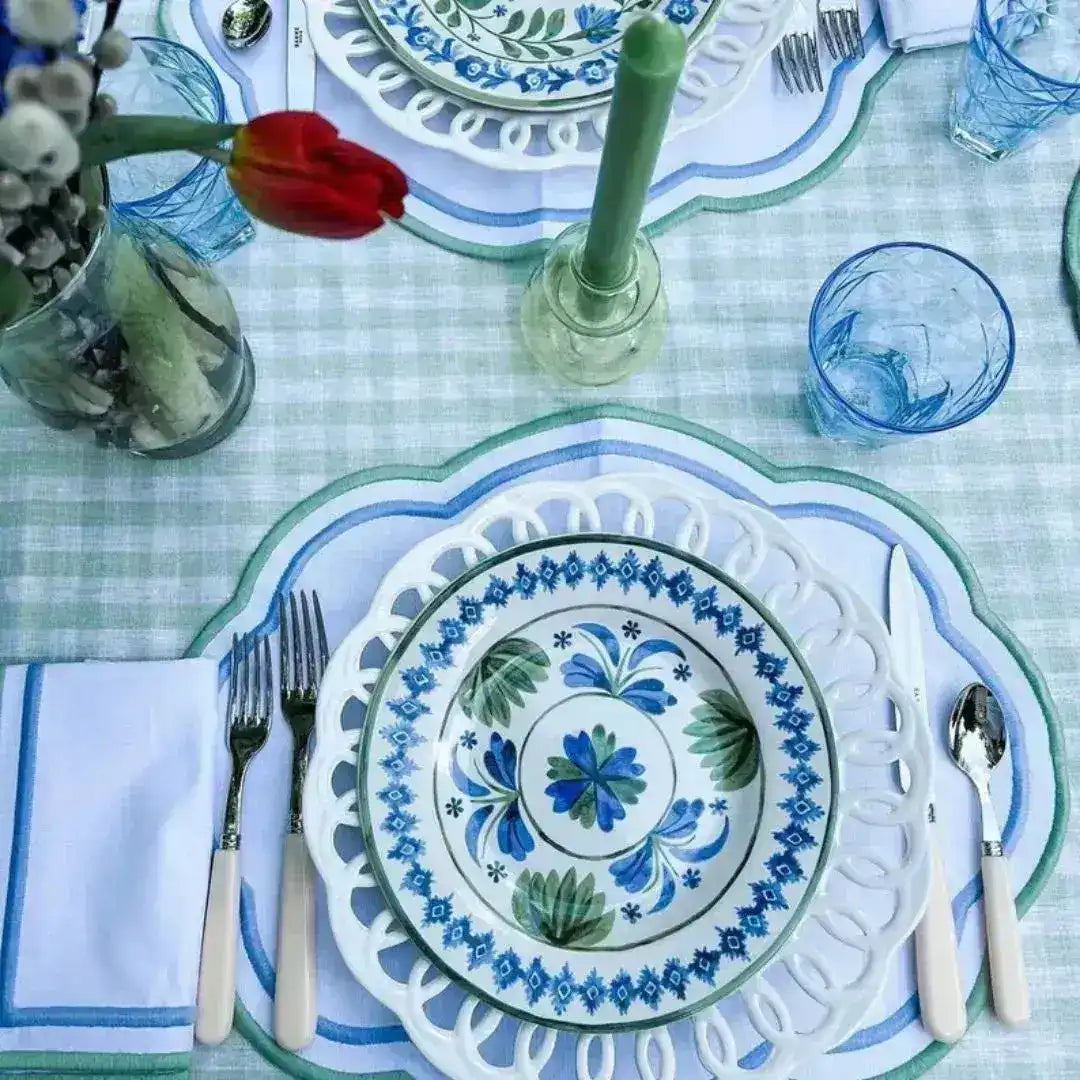 ocean breeze placemats with blue cutout scalloped border on gingham table with folk-art china, green candle and red tulip