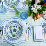 ocean breeze placemats with blue cutout scalloped border on green gingham table with folk-art china, blue tumblers and tulips