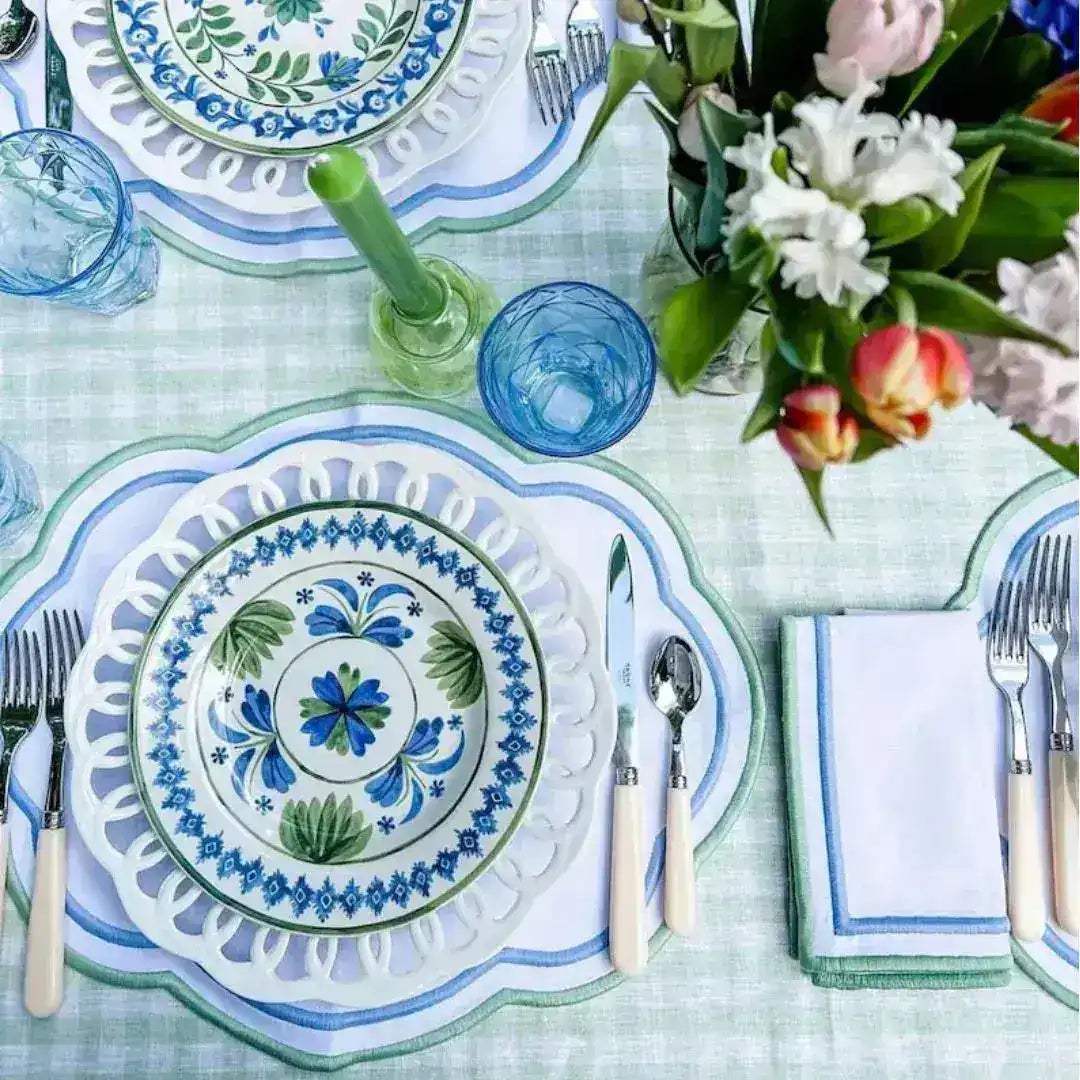 ocean breeze placemats with blue cutout scalloped border on green gingham table with folk-art china, blue tumblers and tulips