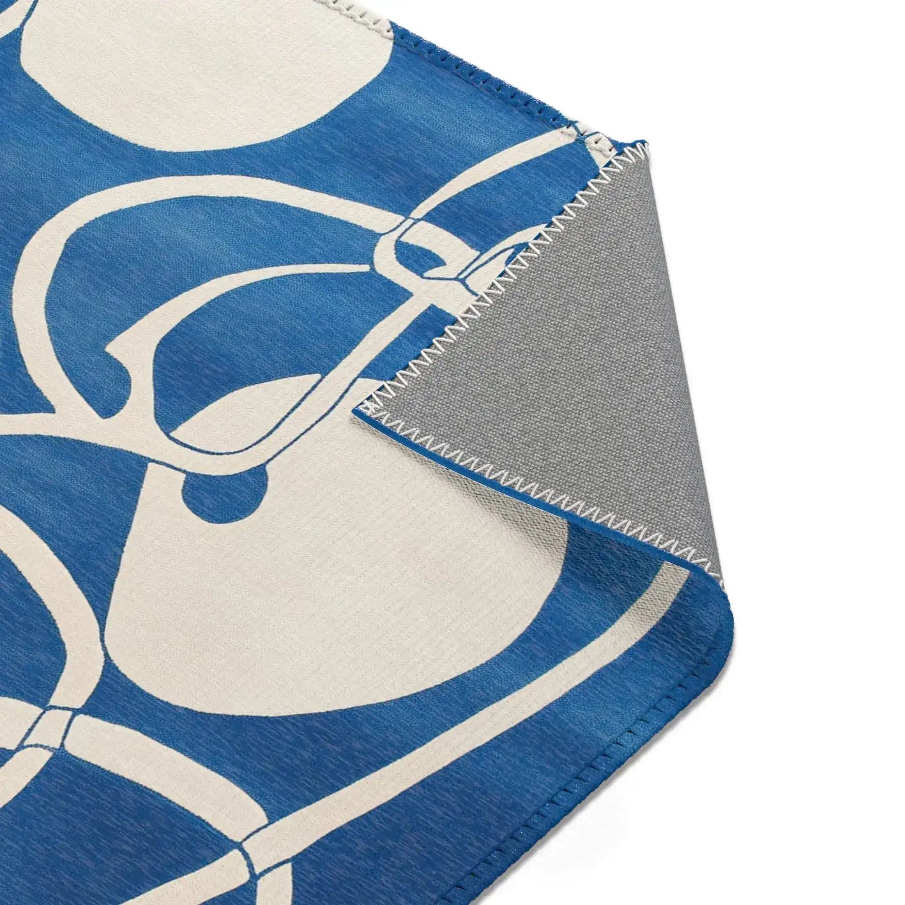 Ocean Flow Abstract Blue and White Rug corner fold showing cobalt blue ground with white abstracted loop pattern, grey backing
