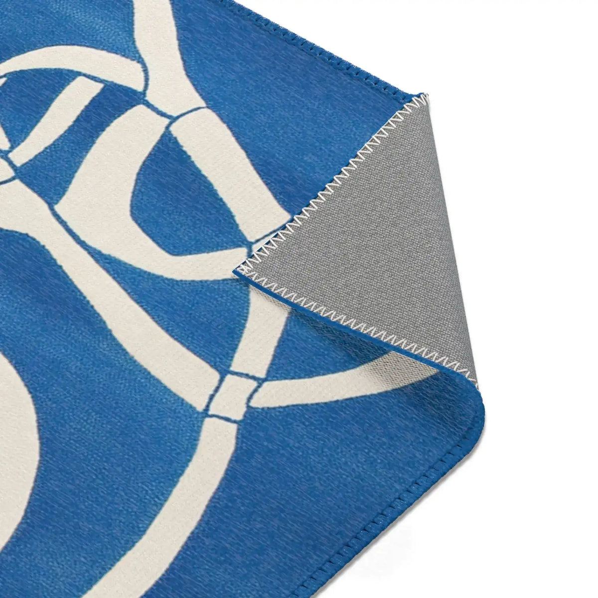 Ocean Flow Abstract Blue and White Rug corner fold with bold white geometric line pattern on cobalt blue, grey backing angled
