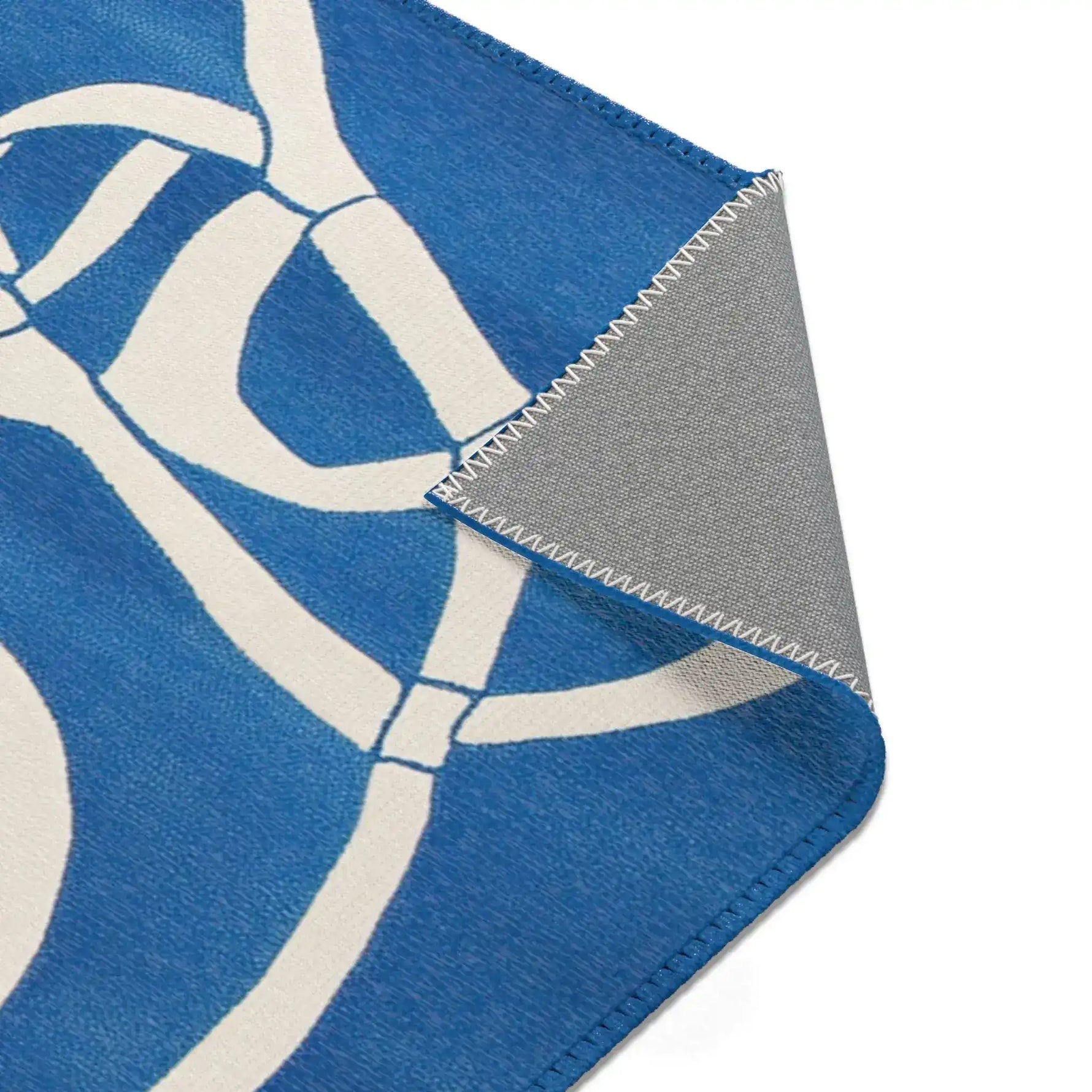 Ocean Flow Abstract Blue and White Rug corner fold with bold white geometric line pattern on cobalt blue, grey backing angled