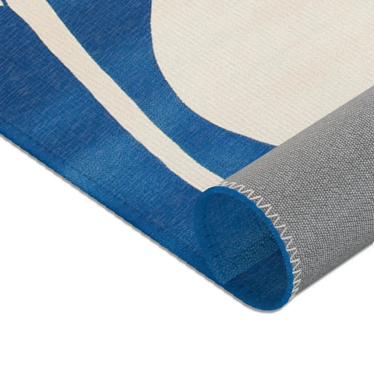 Ocean Flow rug rolled lower edge detail showing cobalt blue and cream flowing curves with grey backing roll visible