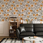 Orange Blossom Symphony Wallpaper with burnt orange blossoms and charcoal grass above chair rail, black leather sofa.