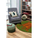 Stylish living room featuring an Orange Tibetan Tiger Green Hand Tufted Round Rug. This wool area rug adds a pop of color with its vibrant tiger design, perfect for large area rugs in an office or living room setting. The rug complements the cozy armchair, decorative pillows, and wooden shelves creating a warm and inviting atmosphere.