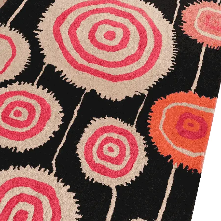 A vibrant Orbit Bloom hand-tufted area rug featuring bold concentric circles in pink and orange hues on a black background. Perfect for adding a splash of style to your dining room or living room. This 8x10 vintage wool rug brings a unique artistic flair to any space, ideal for both living room and dining room rugs.