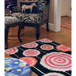 A vibrant Orbit Bloom Hand Tufted Rug in an abstract design featuring concentric circles in pink, orange, and black, perfect for adding a pop of color to a dining room or living room. Ideal for those seeking an 8x10 vintage wool rug to enhance their living space.