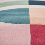 Close-up of a multicolored textured rug with shades of blue, pink, and green.