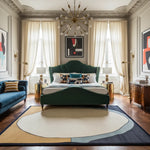 Luxurious bedroom with a green bed, blue sofa, and decorative rug.