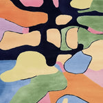 Close-up of a colorful abstract rug with various shapes and colors.