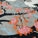 Close-up view of the Oriental Reverie Hand Tufted Rug showcasing intricate floral designs in pink and orange hues against a soft grey wool background. This elegant area rug is perfect for enhancing the aesthetic appeal of bedrooms and living rooms with its artistic flair.