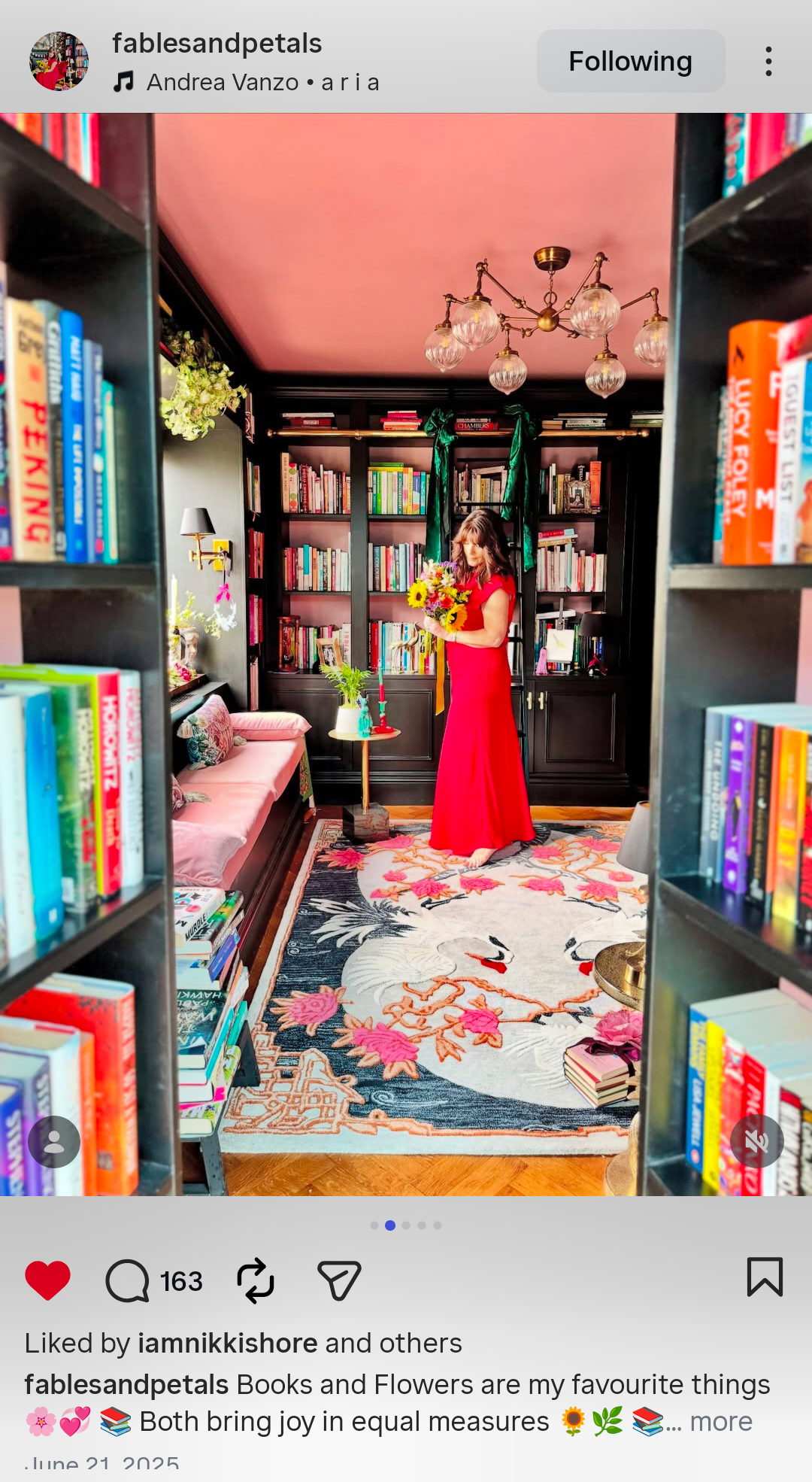 Woman in a red dress standing in a room with bookshelves and decor.