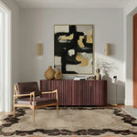 The Ornate Echo Hand Tufted Rug elegantly graces a modern living room, enhancing the space with its vintage design. This large wool area rug features intricate patterns and complements the room's contemporary decor, including a stylish chair and minimalist furniture. Perfect for those seeking living room area rugs that combine classic charm with modern aesthetics.