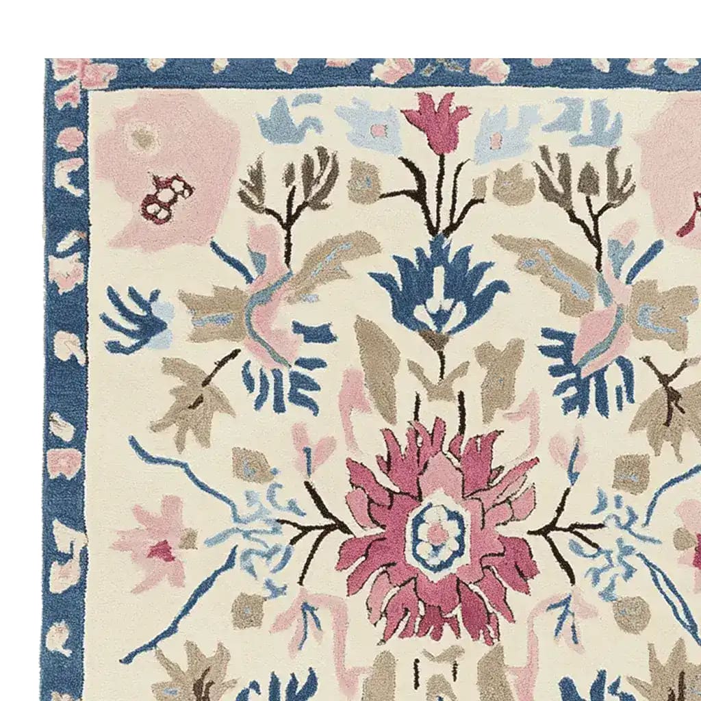 Close-up view of an ornate flora fringe hand-tufted rug, showcasing intricate floral patterns in pink, blue, and beige hues. This area rug is perfect for adding elegance to any living room, making it a standout among living room area rugs. Crafted from wool, it's an ideal large living room rug option.