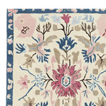 Close-up view of an ornate flora fringe hand-tufted rug, showcasing intricate floral patterns in pink, blue, and beige hues. This area rug is perfect for adding elegance to any living room, making it a standout among living room area rugs. Crafted from wool, it's an ideal large living room rug option.