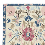 Close-up view of an ornate flora fringe hand-tufted rug, showcasing intricate floral patterns in pink, blue, and beige hues. This area rug is perfect for adding elegance to any living room, making it a standout among living room area rugs. Crafted from wool, it's an ideal large living room rug option.