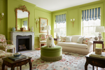 Living room with green walls, floral rug, white furniture, and decorative elements.