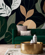 Oversized botanical leaf wallpaper behind emerald velvet sofa with hammered gold drum table
