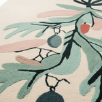 Close-up of a decorative rug with green leaves and pink accents on a beige background