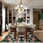 A beautifully styled dining room featuring a Palatial Blooms Hand Tufted Area Rug. The vintage wool rug adds charm and elegance to the space, with its intricate floral patterns and vibrant colors. Perfect for a formal dining room setting, the rug lies beneath a polished wooden dining table surrounded by stylish chairs, enhancing the cozy yet sophisticated ambiance.