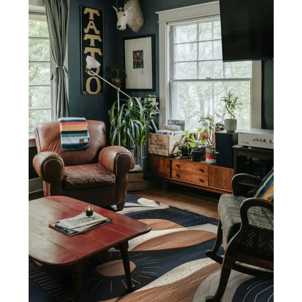 Cozy living room featuring a Palm Echoes Hand Tufted Rug, an elegant area rug with a contemporary design. The wool rug showcases a blend of vintage and modern styles, enhancing the room's decor with its artistic patterns. Surrounded by classic leather and wooden furniture, this area rug is perfect for living room or office spaces, adding warmth and style.