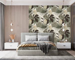 Vintage Glamour palm and monstera wallpaper as bedroom accent; sage and dark leaves on cream behind gray upholstered bed
