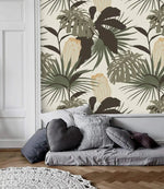 Vintage Glamour palm and monstera wallpaper panel above low gray floor daybed with mixed cushions; herringbone wood floor