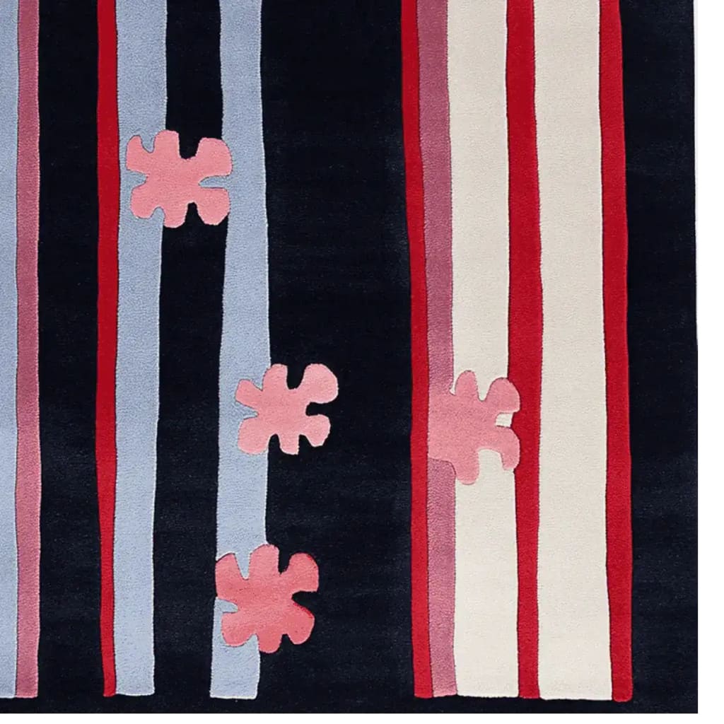 A vibrant area rug showcasing a modern design with bold vertical stripes in blue, red, and white, accented by abstract pink floral patterns. This contemporary wool rug adds a stylish touch to any living room, perfect for those seeking unique area rugs for their home decor.