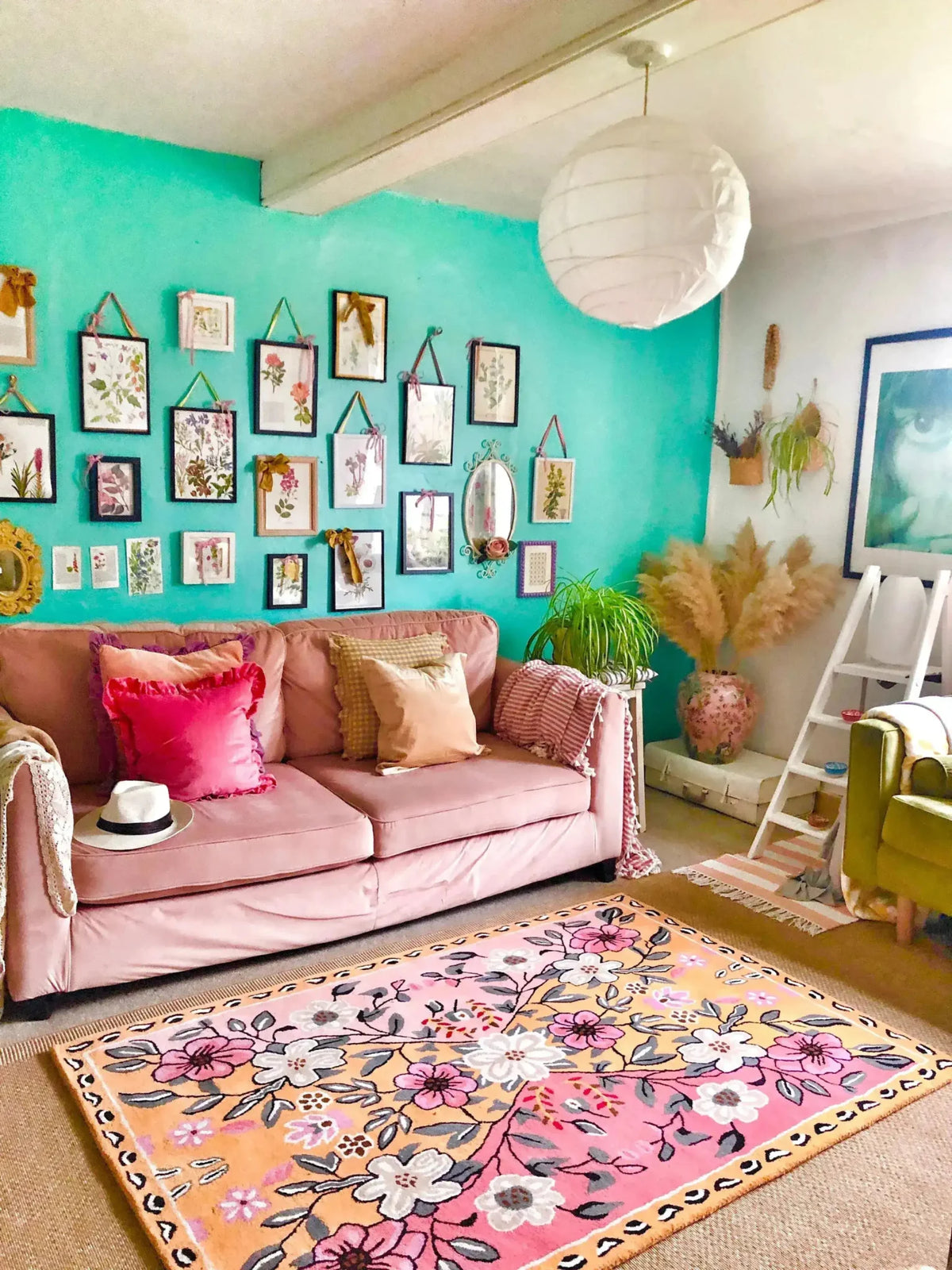 A vibrant living room showcasing a Pastel Paradise Hand Tufted Rug with a beautiful floral design. This area rug features pink and orange hues, perfect for adding a vintage touch to your living room. The wool rug complements the cozy pink sofa adorned with colorful cushions, creating an inviting and stylish space. Ideal for those seeking living room area rugs that combine elegance and comfort.